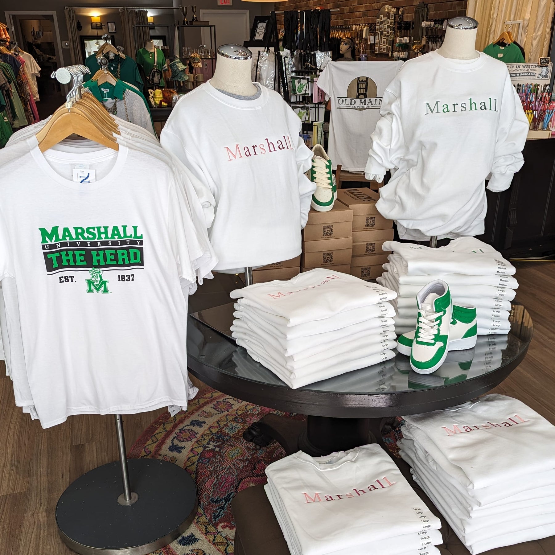 a table with a selection of white marshall sweatshirts and a hanging white marshall tee shirt
